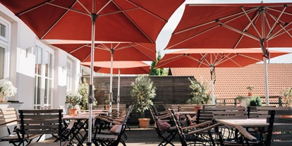 Golfurlaub - Restaurant - Terrasse mit roten aufgespannten Schirmen - Klostermaier - Hotel & Restaurant